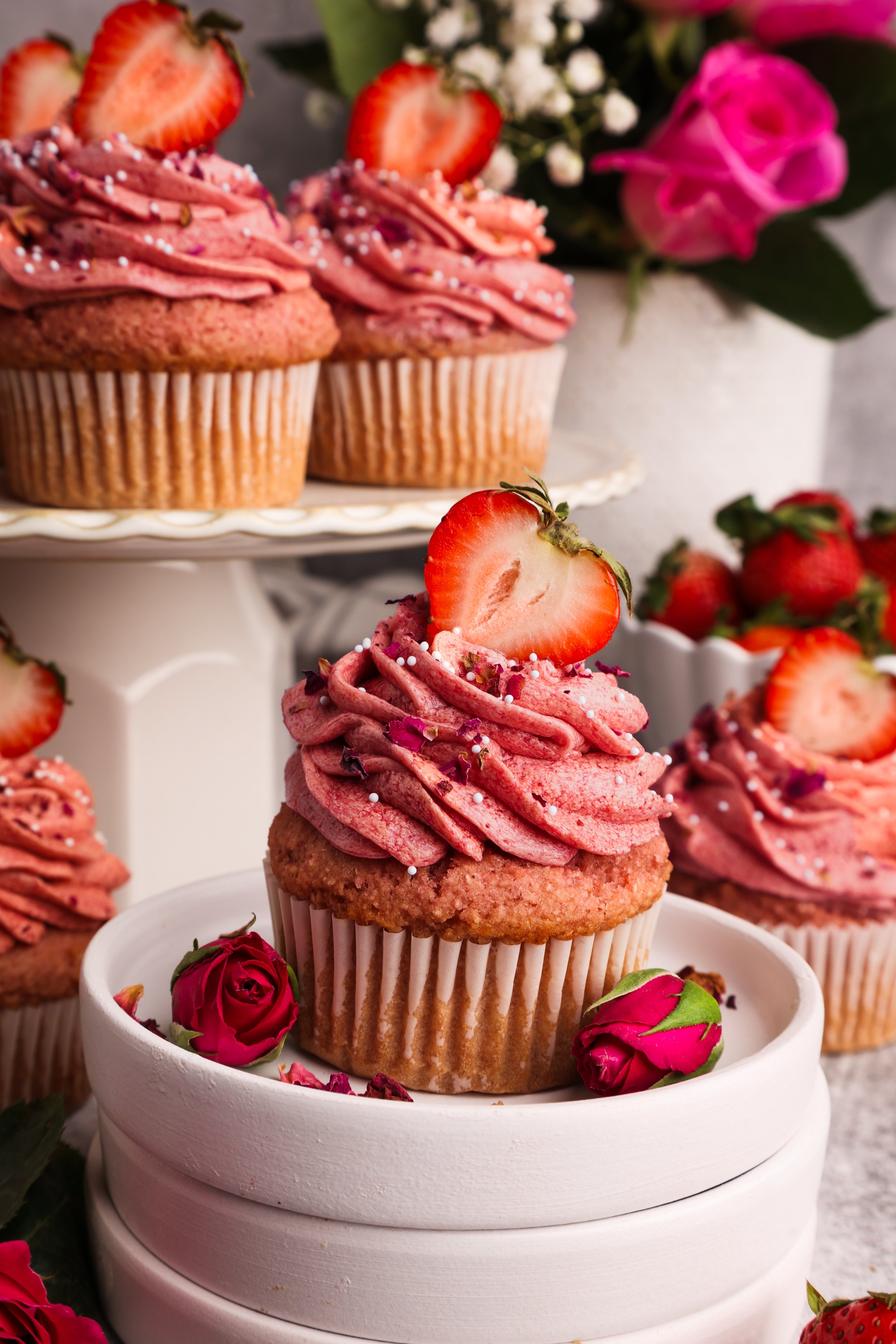 Cupcakes with pink frosting garnished with a sliced strawberry
