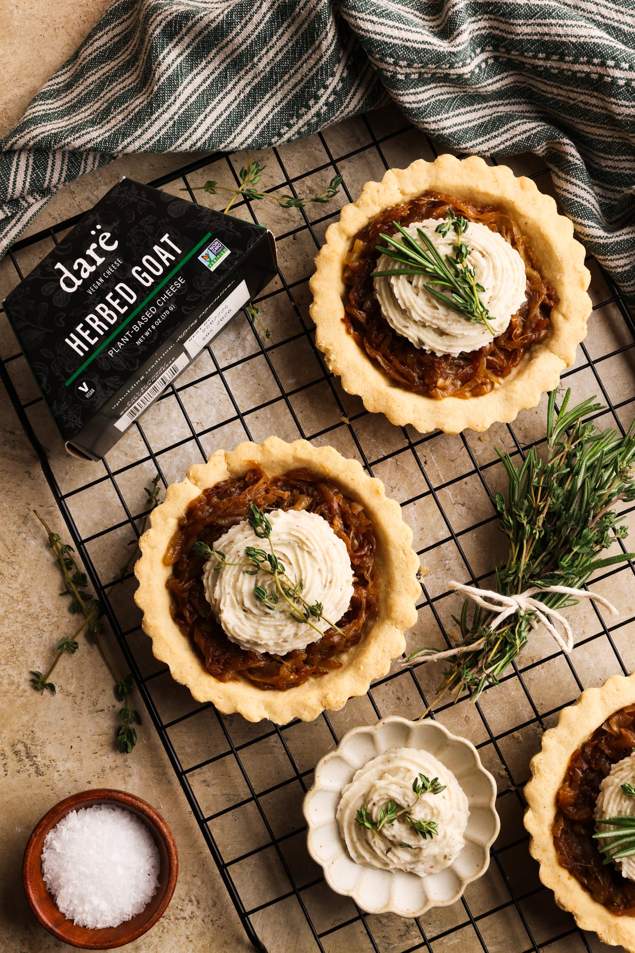 Caramelized onion tarts on a wire rack surrounded by ingredients