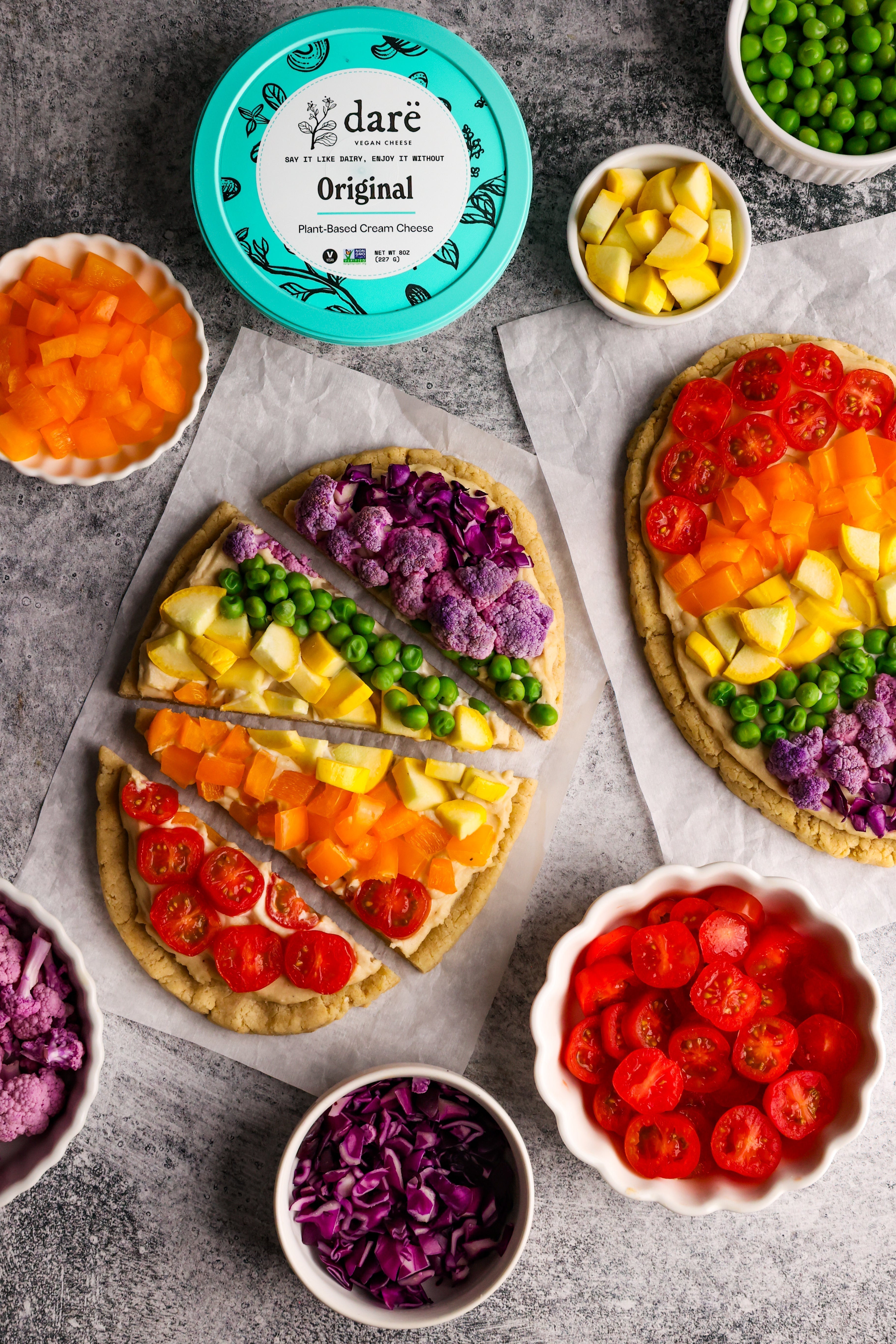 Colorful flatbread surrounded by cut up vegetables and dare original cream cheese