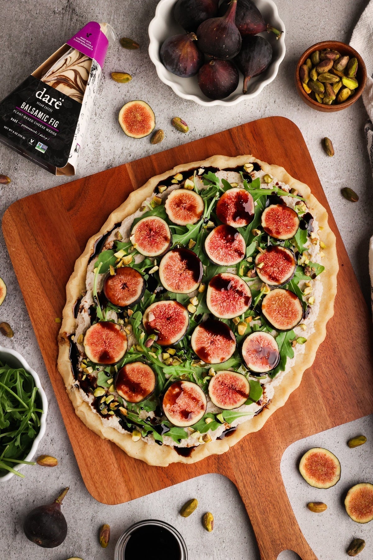 Vegan balsamic fig flatbread on a gluten-free almond flour crust topped with fresh figs, arugula, and pistachios.