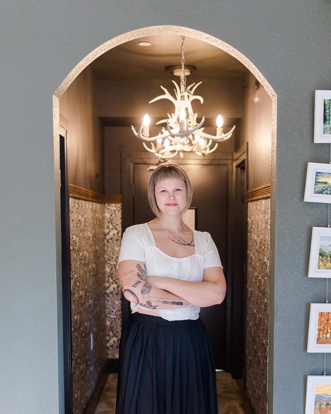 Blonde woman stands in hallway with arms crossed