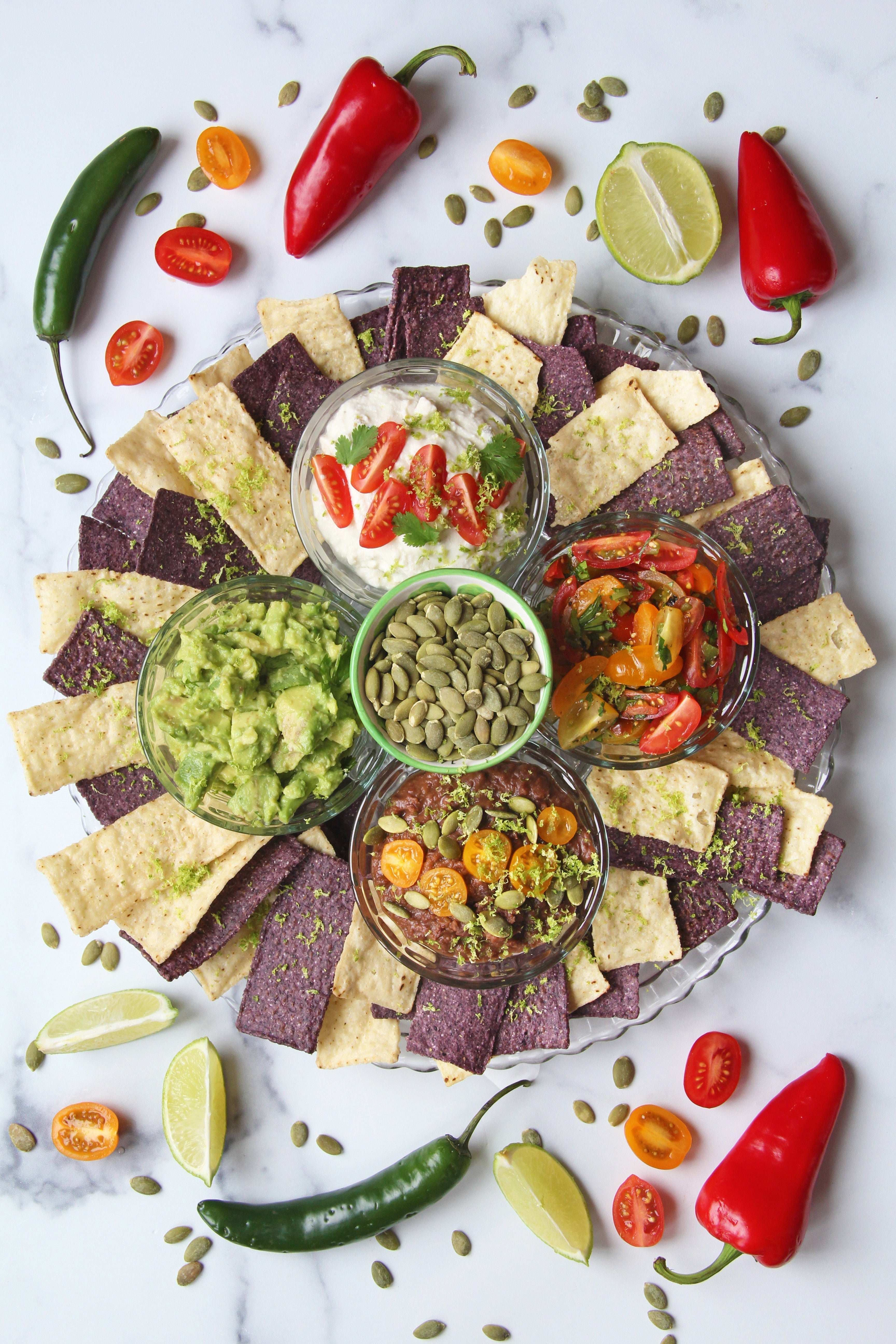Party platter with dips and chips stylized with peppers on a white background