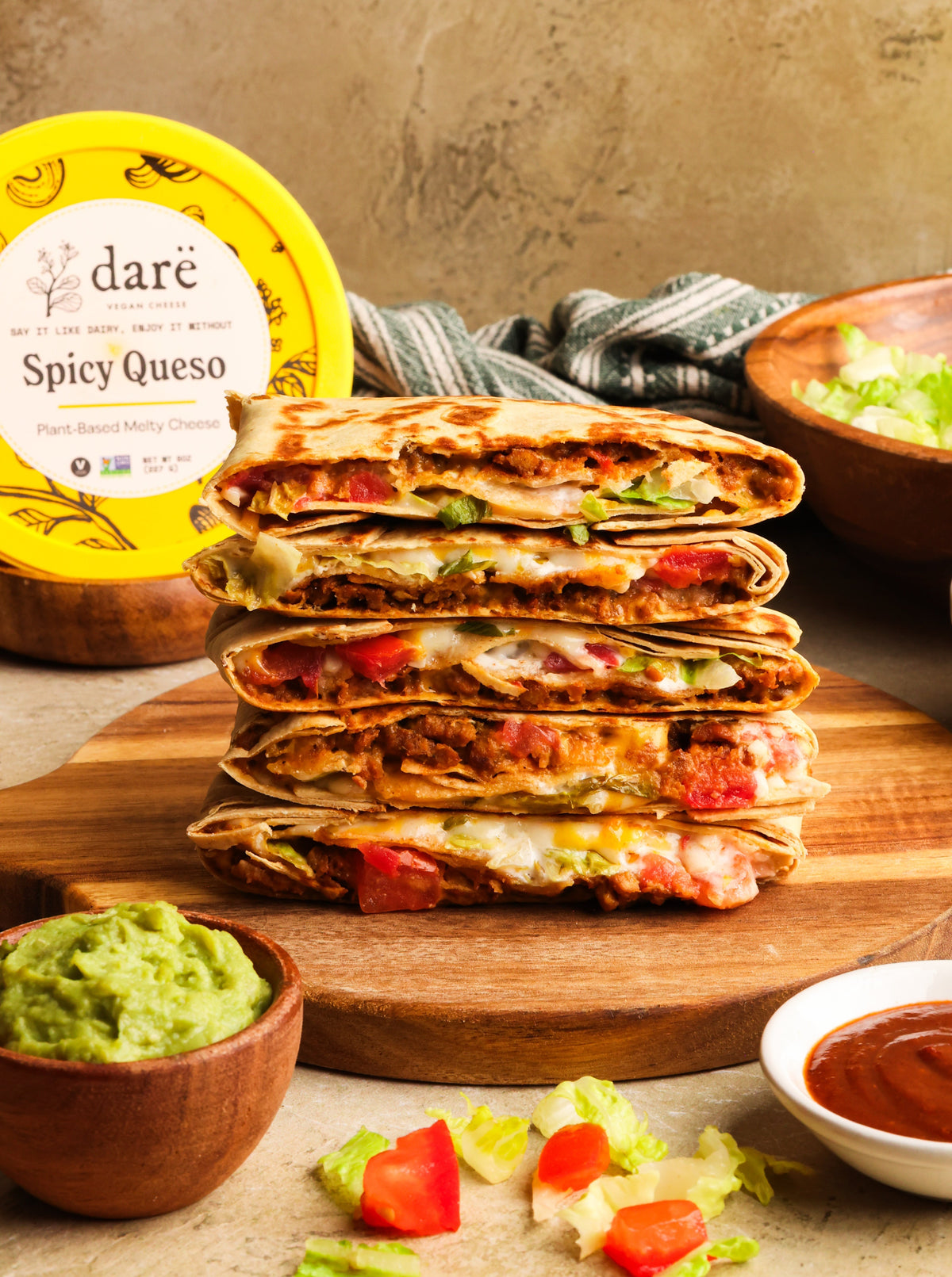Stacked vegan crunchwrap supremes with Dare vegan cheese spicy queso in the background