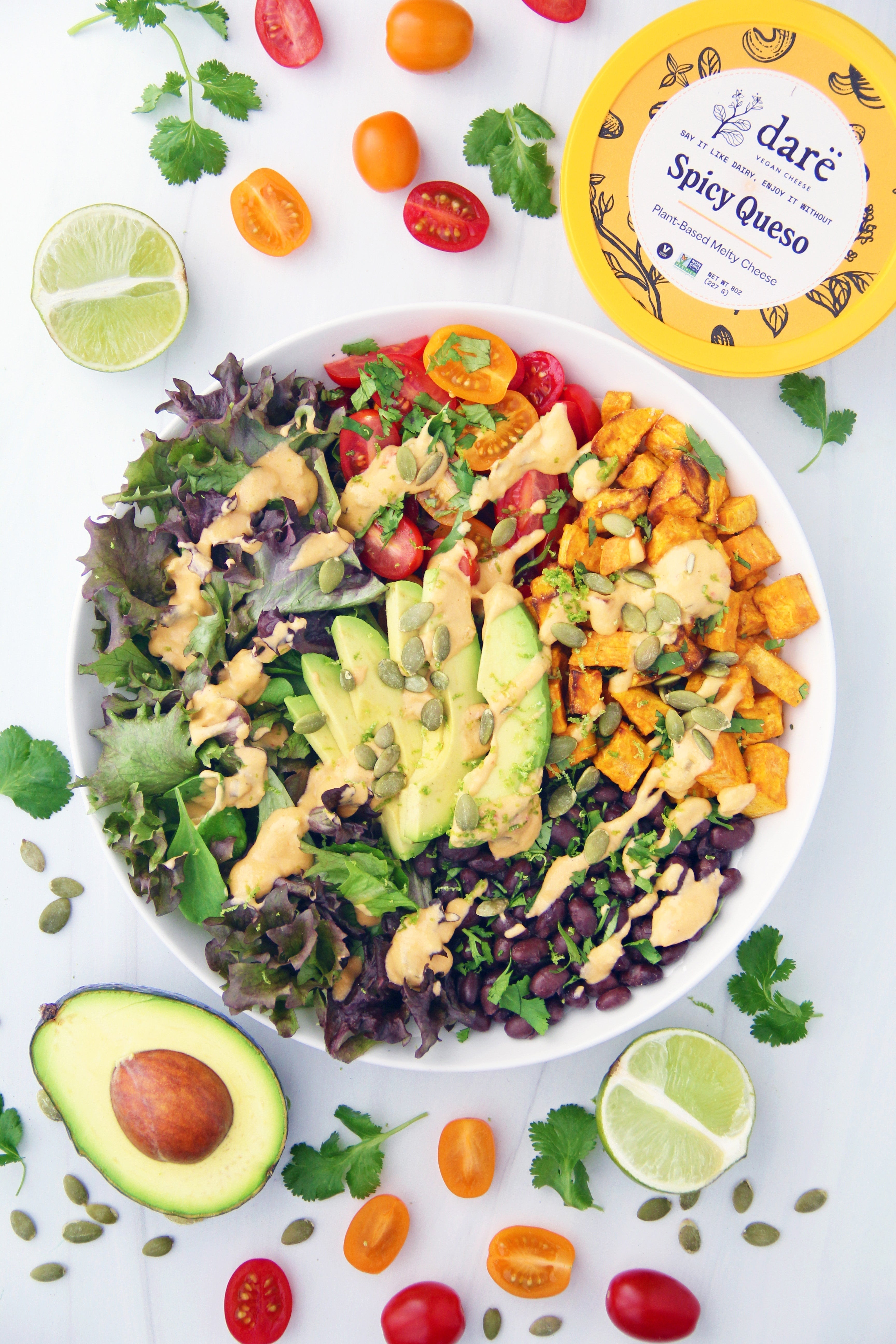 Taco salad with black beans, sweet potato, greens, tomato and queso
