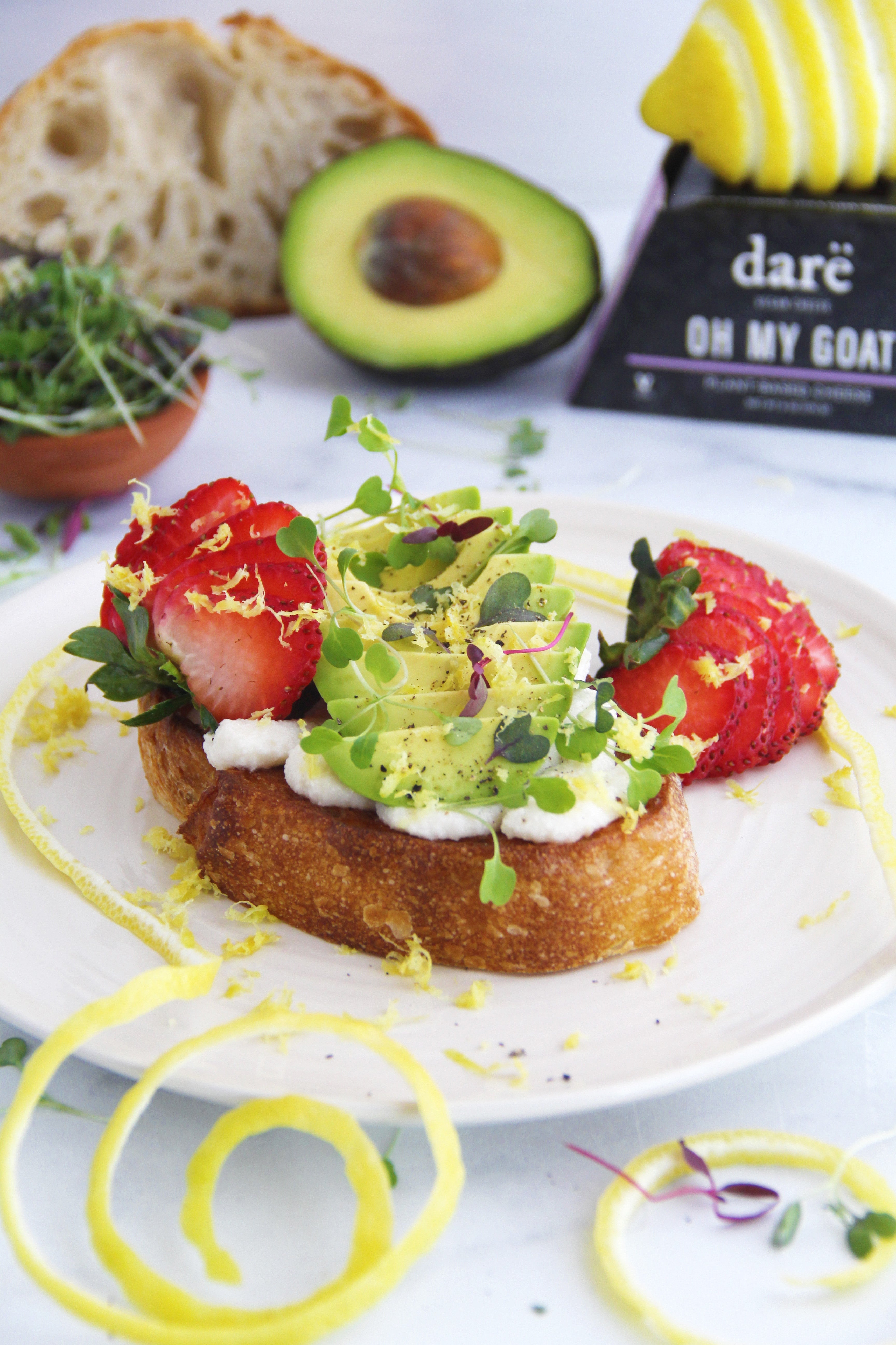 Avocado toast topped with strawberries, lemon zest and microgreens