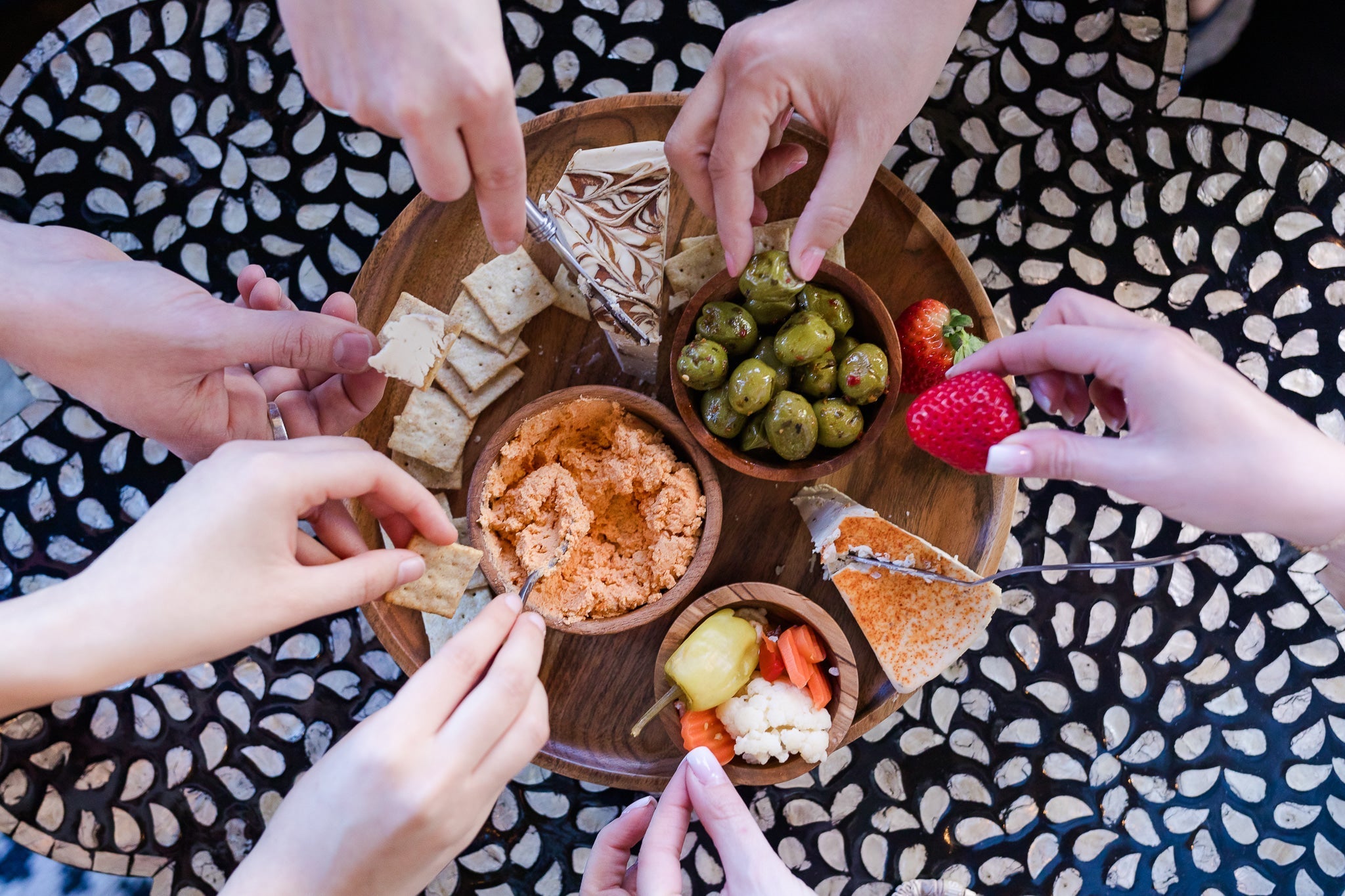 hands reaching into snack on vegan cheeseboard
