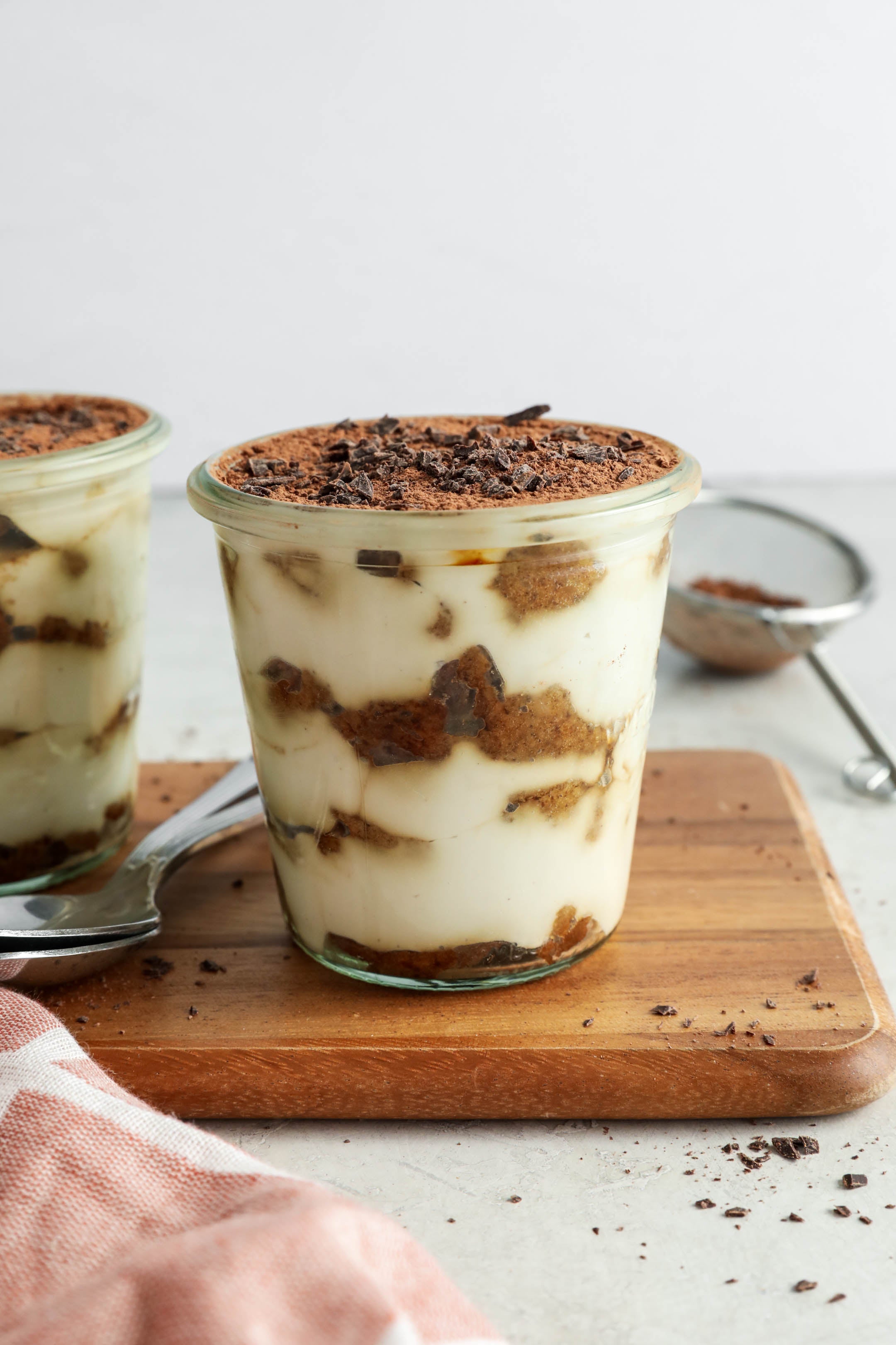 Cup of layered tiramisu on a wooden board