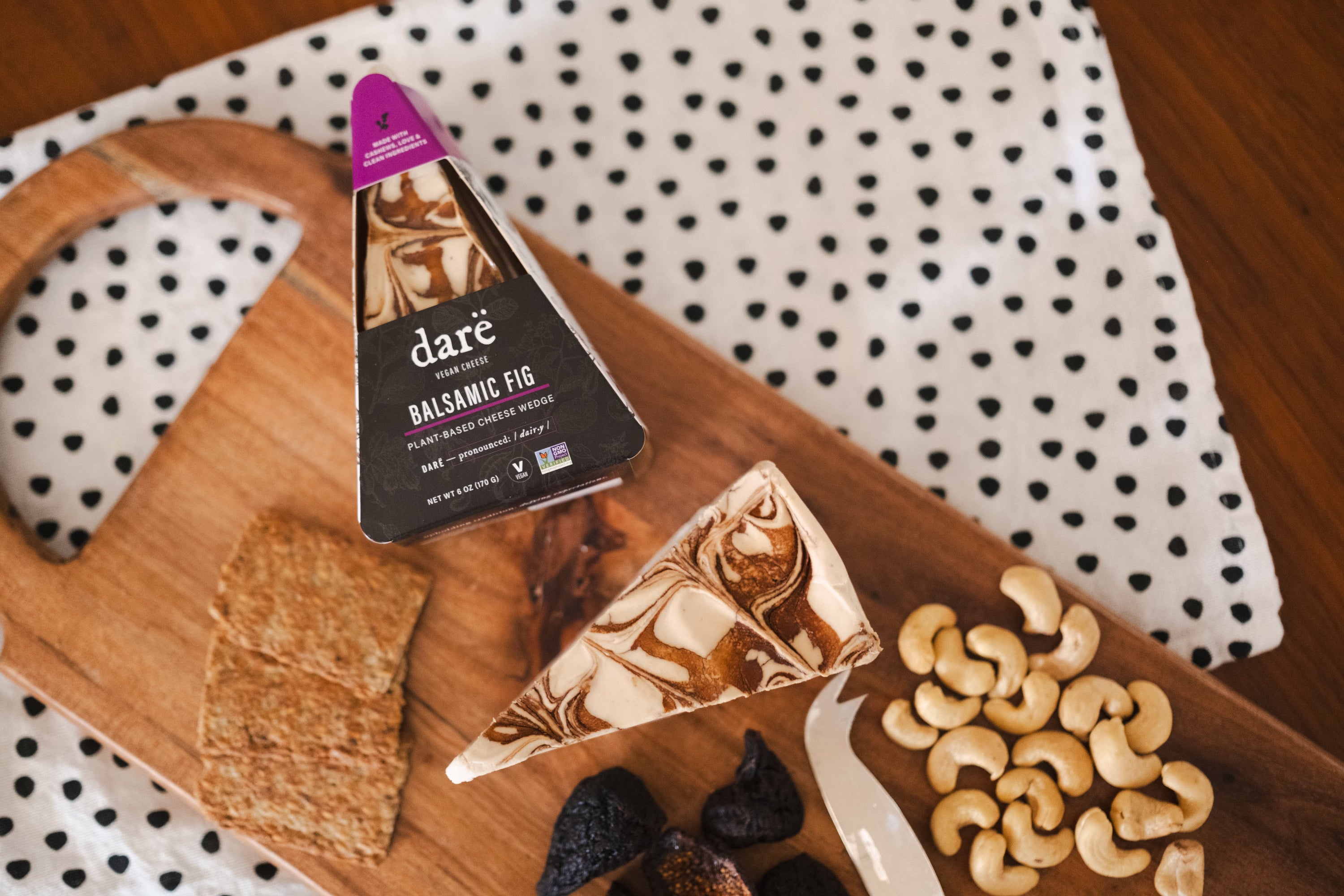 Darë Balsamic Fig Cheese Wedge on a cheeseboard with crackers, cashews, and dried figs