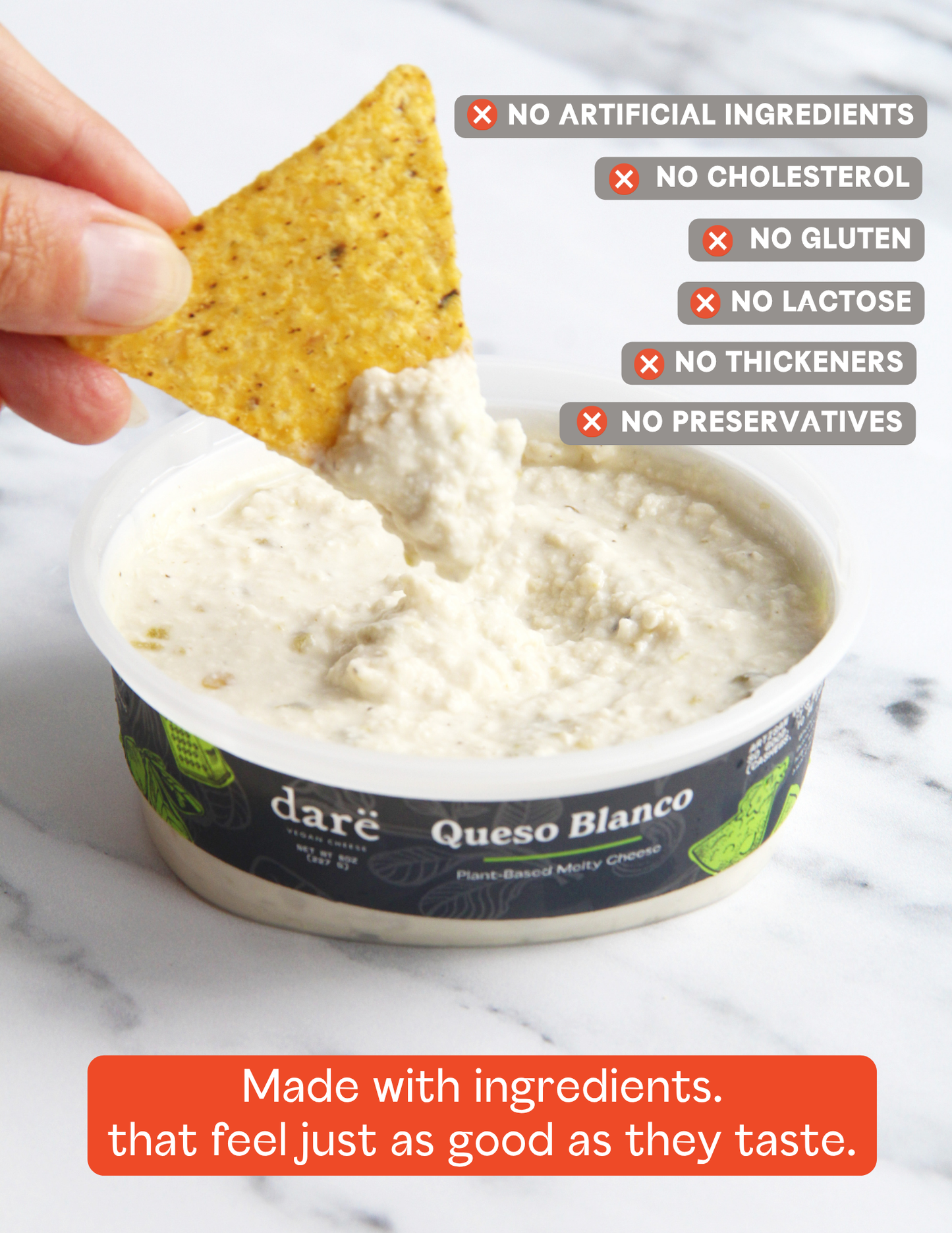 A hand holds a tortilla chip above a tub of daré Queso Blanco cheese dip on a light marble surface. The label reads 'daré Queso Blanco' and includes product claims such as no artificial ingredients, no cholesterol, no gluten, no lactose, no thickeners, and no preservatives.