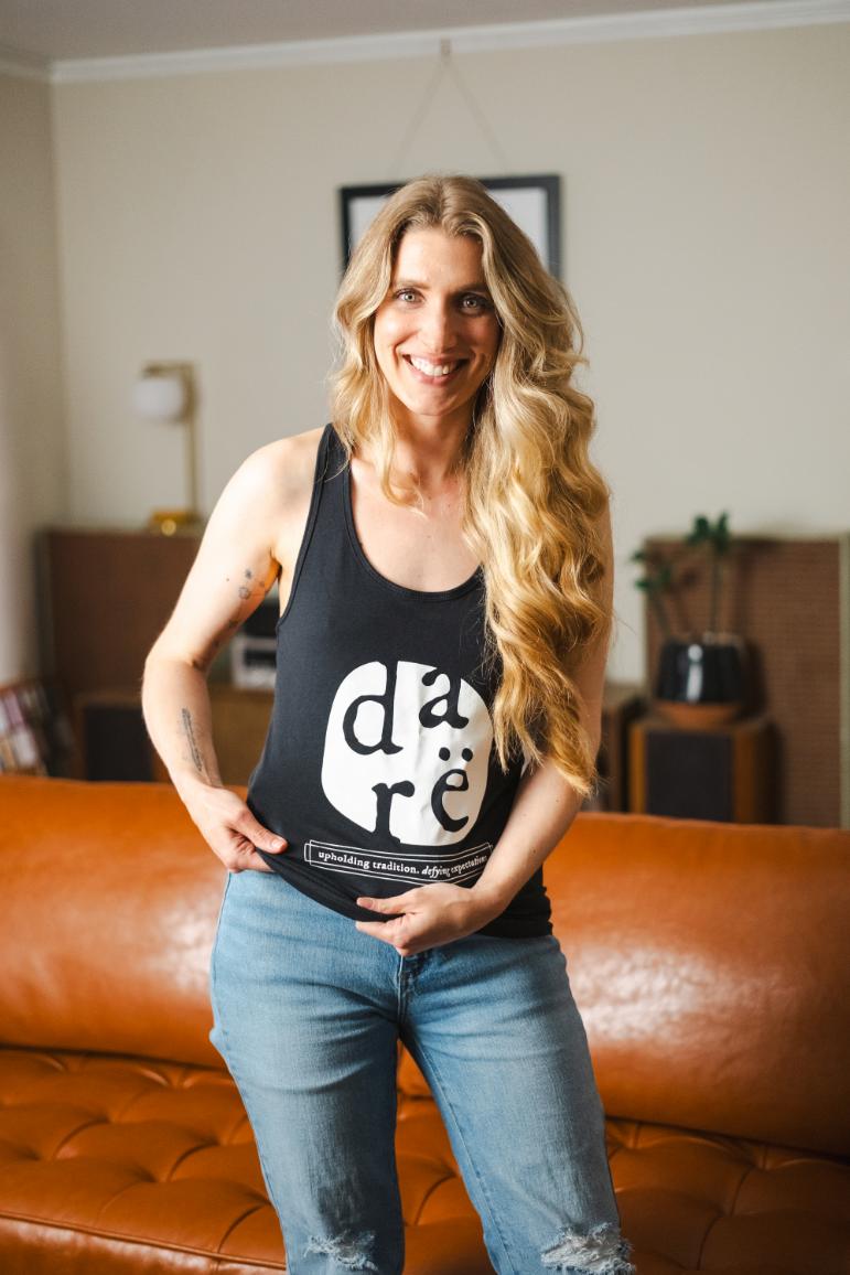 black Racerback Tank top shirt with white lettering. reads dare upholding tradition, defying expectation