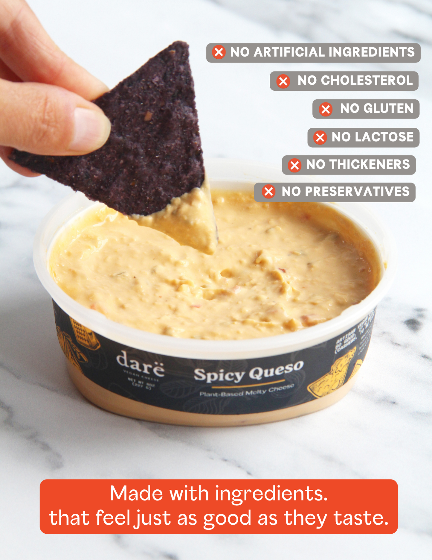 A hand dipping a dark tortilla chip into a tub of daré Spicy Queso hand-based melted cheese. The image features text overlays highlighting product benefits (no artificial ingredients, cholesterol, gluten, lactose, thickeners, or preservatives) and a tagline at the bottom.