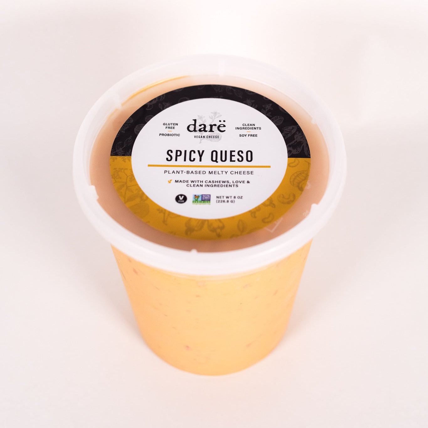 Container of 'dare Spicy Queso' on a white background