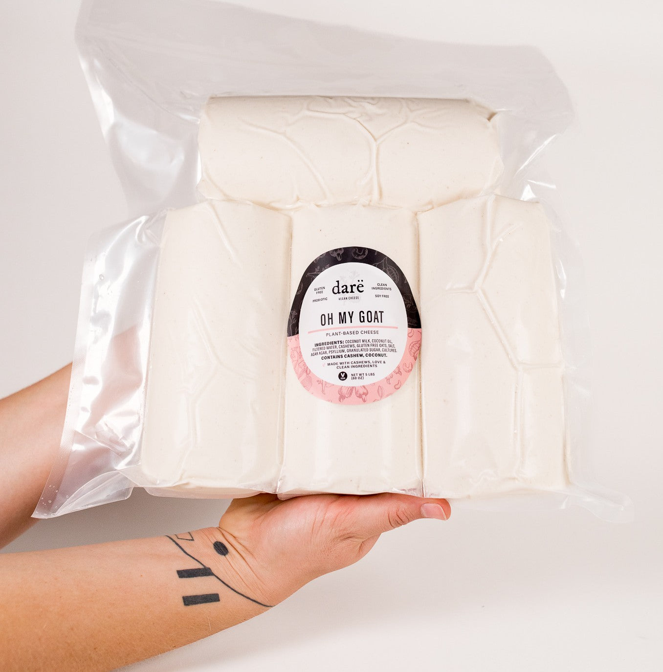 Person holding a package of 'Oh My Goat' cheese with a visible brand label in a 5 pound bag.