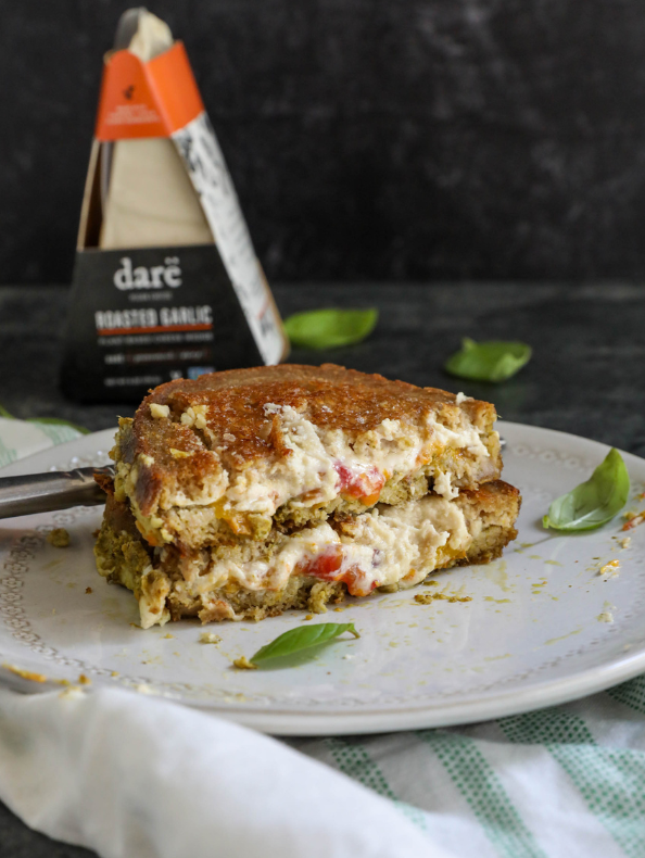 Slice of grilled cheese on a plate with 'dare' roasted garlic product in the background